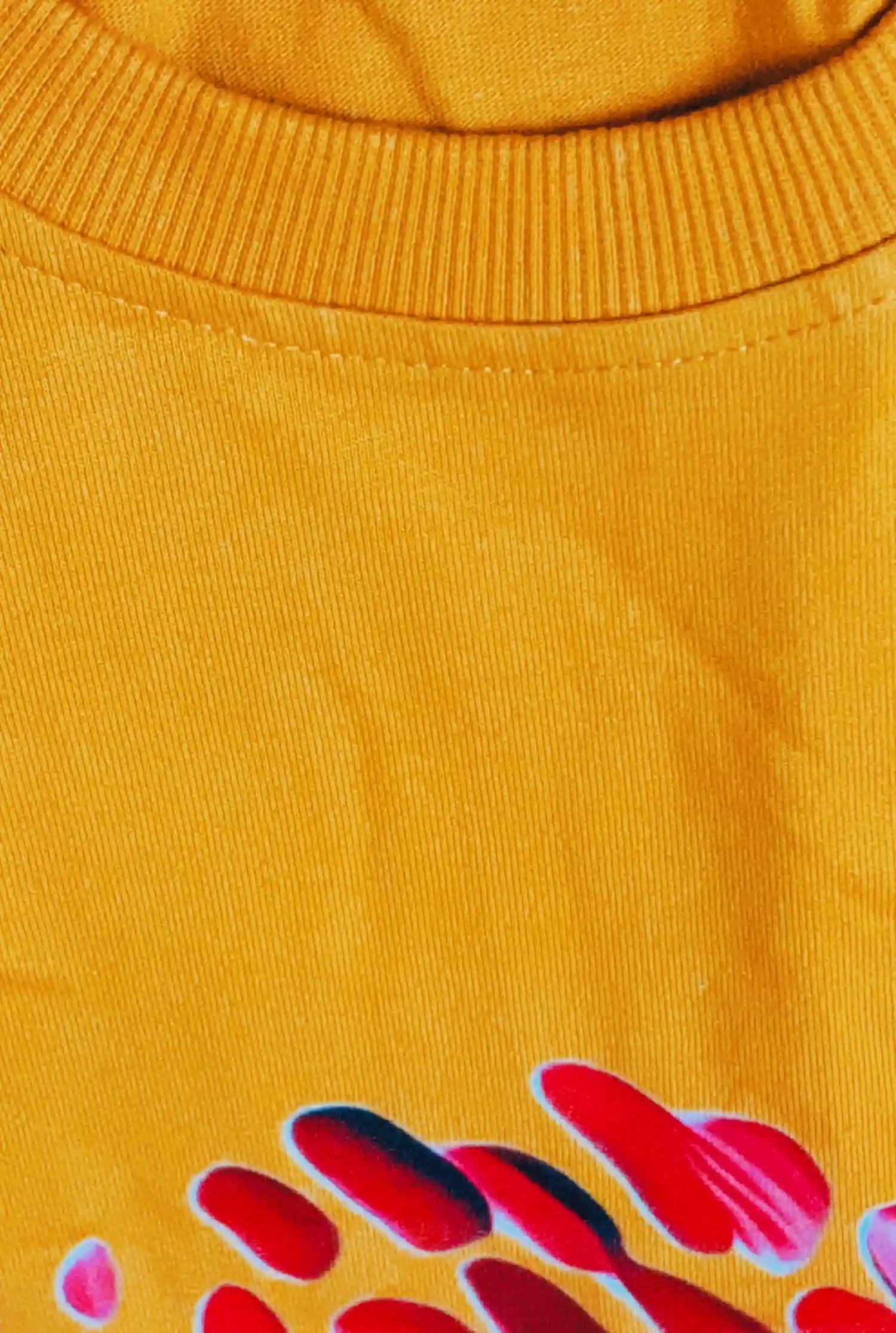 Close-up of a yellow garment with red and pink abstract designs.